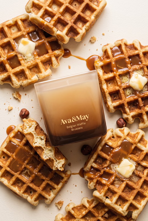 Die Kerze Ava&May Belgian Waffle (220 Gramm) liegt auf einem Tisch, umgeben von frisch gebackenen belgischen Waffeln, die mit Karamellcreme und Butter gefüllt sind