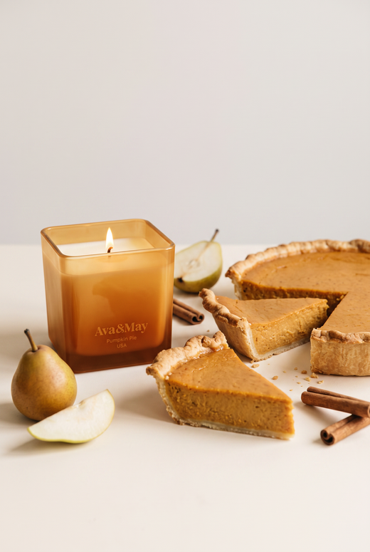 Die Kerze Pumpkin Pie (220 g) von Ava&May, angezündet, mit einer Kürbiskuchen-Tarte mit Birnen und Zimt