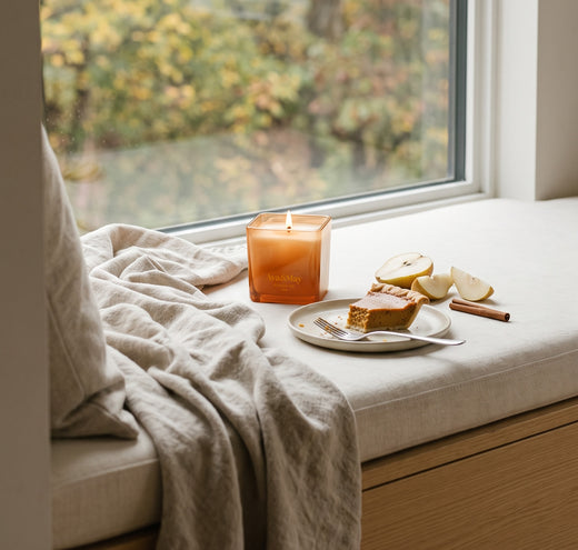 Die Pumpkin Pie Kerze (220 g) von Ava&May brennt auf einer Fensterbank neben einem Stück Kürbiskuchen mit Birne und Zimt
