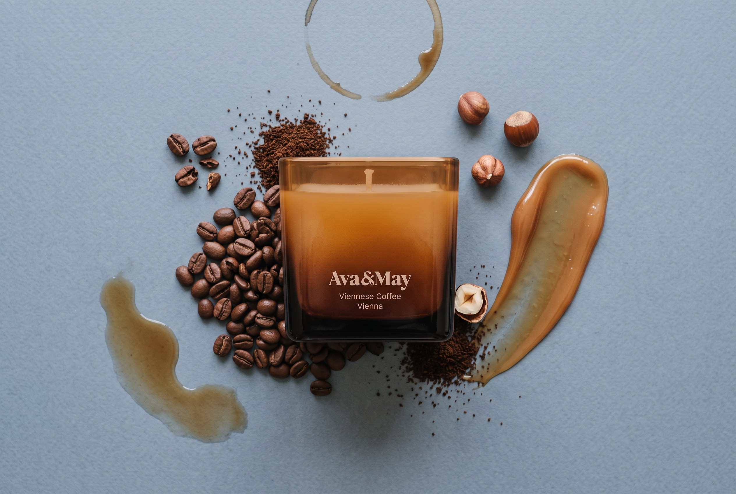 Ava&May-Kerze Viennese Coffee, umgeben von Haselnüssen, Kaffeebohnen, Karamellsauce und Kaffee